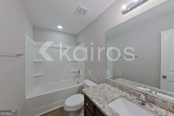 a bathroom with a granite countertop sink a toilet and shower