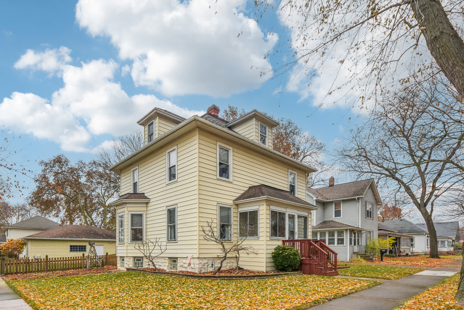 a view of a white house next to a yard with big trees
