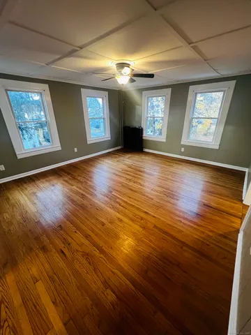 a view of an empty room with window and wooden floor