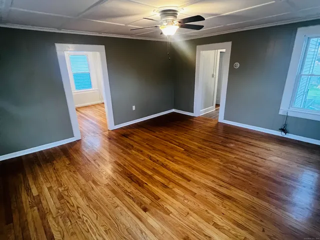 a view of an empty room with wooden floor and a window