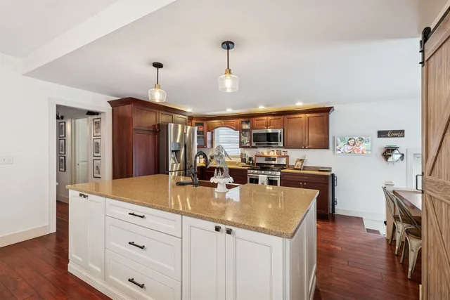 a kitchen with a stove a refrigerator and a dining table with wooden floor