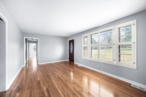 a view of an empty room with wooden floor and a window
