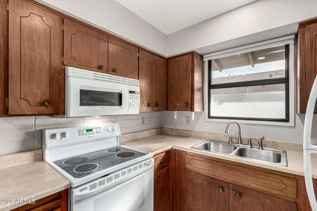 a kitchen with granite countertop a sink stove and microwave