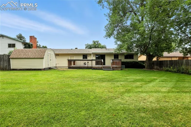 a view of a house with a big yard and large tree