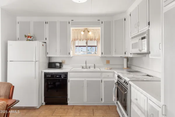 a kitchen with stainless steel appliances granite countertop a dining table chairs refrigerator and window