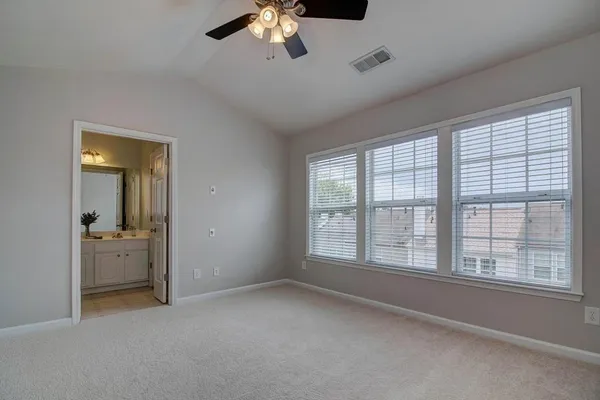 an empty room with chandelier fan and windows