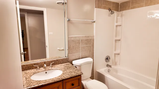a bathroom with a granite countertop sink toilet and shower
