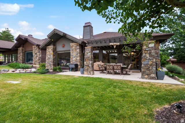 4892 Eagle Rdg Drive Eden, UT 84310 - Photo 29 of 39 Stone and wood-sided exterior featuring multiple large windows, a covered patio with a pergola, and an expansive lawn