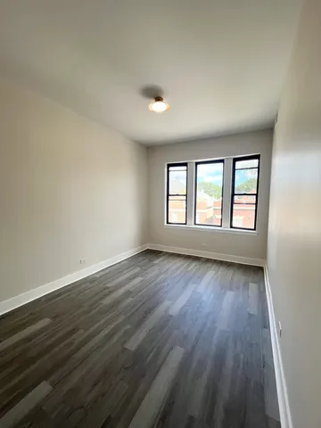 a view of an empty room with wooden floor and window