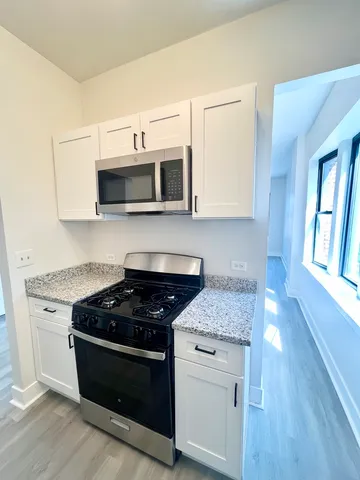 a kitchen with stainless steel appliances granite countertop white cabinets stove top oven and sink