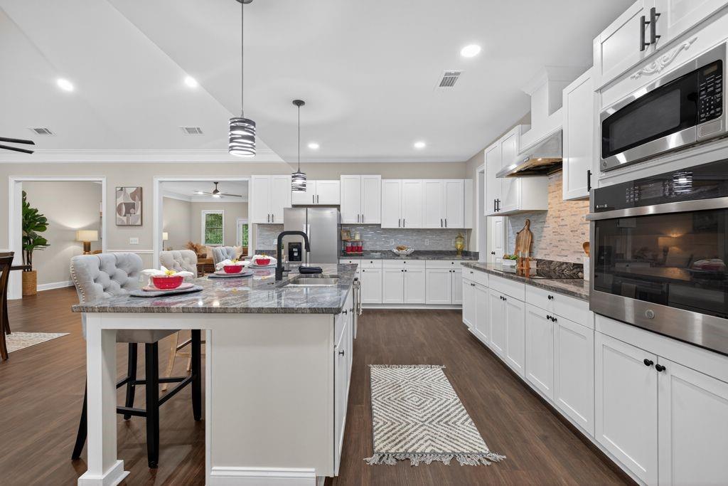 338 Mt Zion Road Oxford, GA 30054 - Photo 12 of 33 a kitchen with stainless steel appliances granite countertop a stove top oven a sink dishwasher a dining table and chairs with white cabinets