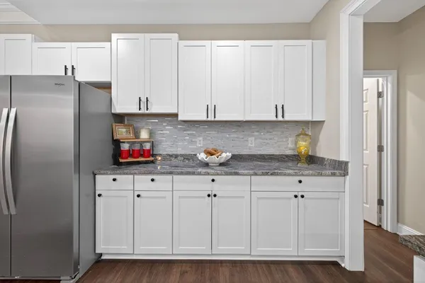 a kitchen with stainless steel appliances granite countertop a refrigerator a stove and white cabinets