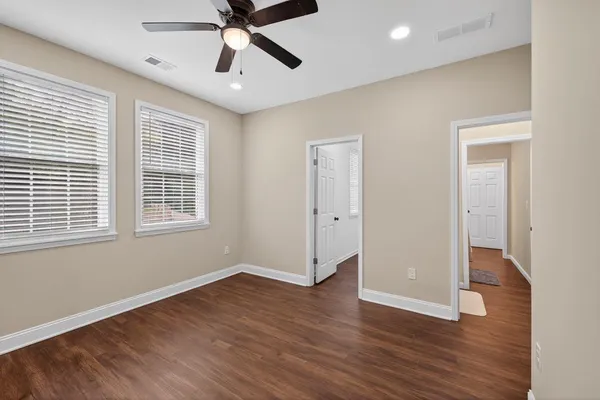 a view of empty room with wooden floor and fan