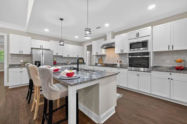 a kitchen with stainless steel appliances granite countertop a table chairs sink refrigerator and microwave