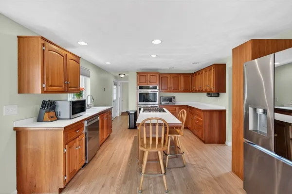 a kitchen with stainless steel appliances granite countertop a refrigerator a stove top oven a sink dishwasher and wooden cabinets with wooden floor