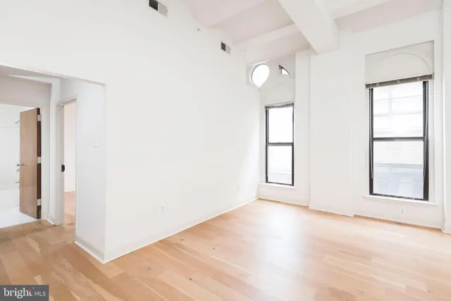 an empty room with wooden floor cabinet and windows