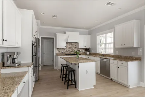 a kitchen with granite countertop a sink window and cabinets