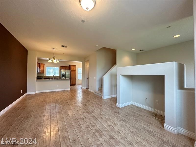 4650 Ranch House Road, Unit 95 North Las Vegas, NV 89031 - Photo 30 of 50 Unfurnished living room featuring a chandelier, light wood-style floors, and stairway