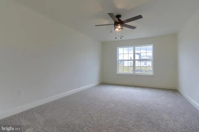 an empty room with ceiling fan and windows