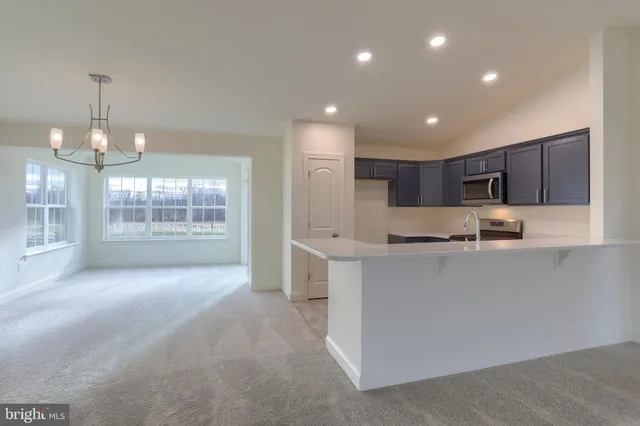 a large kitchen with kitchen island a sink a stove a refrigerator and a dining table with wooden floor