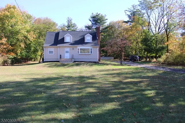 a view of a big house with a big yard plants and large trees