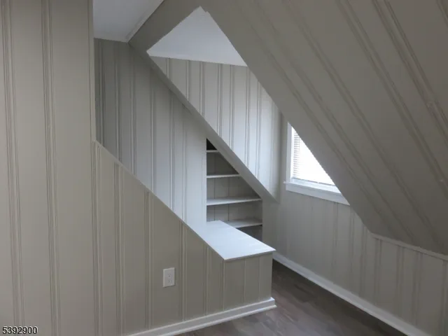 an empty room with wooden floor fridge and windows