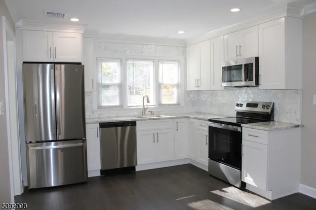 a kitchen with granite countertop a refrigerator stove and microwave