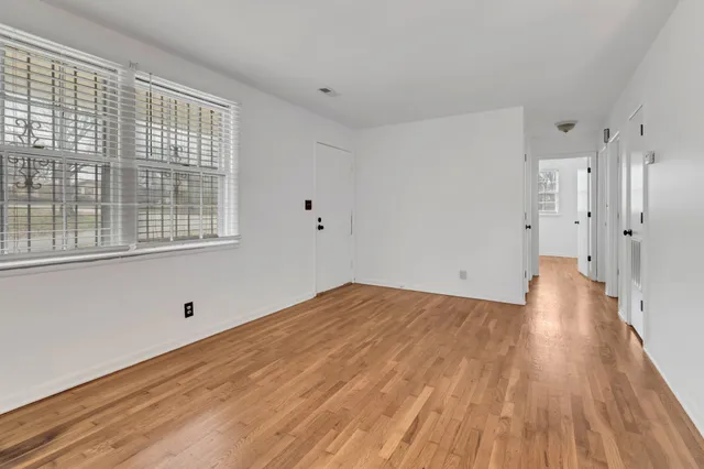 a view of an empty room with wooden floor and windows