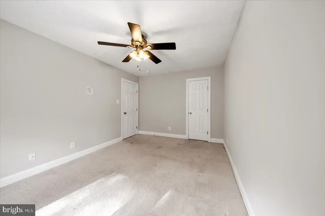 an empty room with a ceiling fan and a window