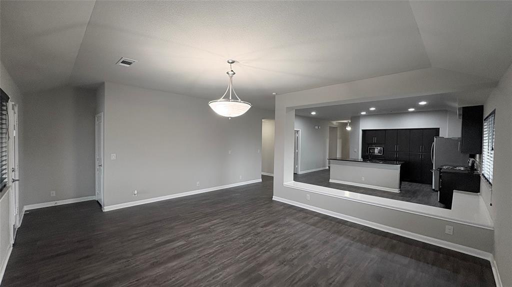 2101 Long Forest Road Forney, TX 75126 - Photo 6 of 15 an empty room with wooden floor and kitchen view