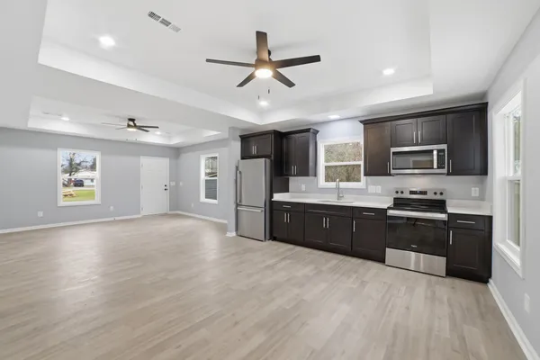 a large kitchen with stainless steel appliances granite countertop a refrigerator oven a sink dishwasher and a stove with wooden floor