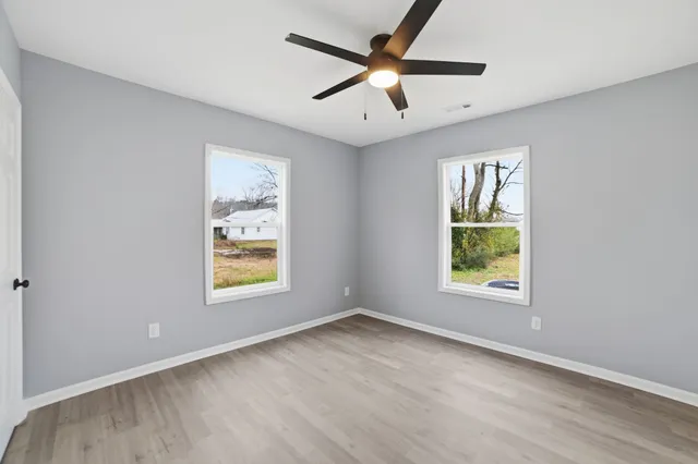 an empty room with window and ceiling fan