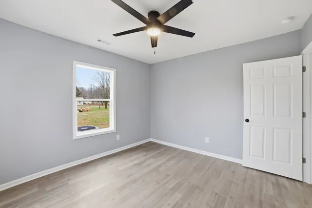 a view of an empty room with a window and wooden floor