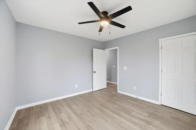 an empty room with wooden floor and ceiling fan