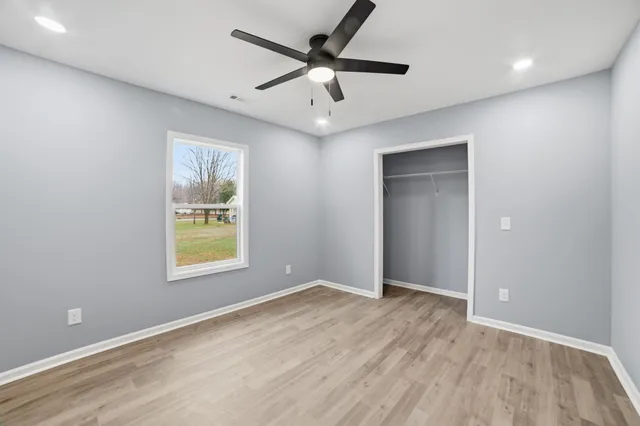 an empty room with a window and a ceiling fan