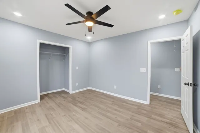 an empty room with wooden floor and a ceiling fan