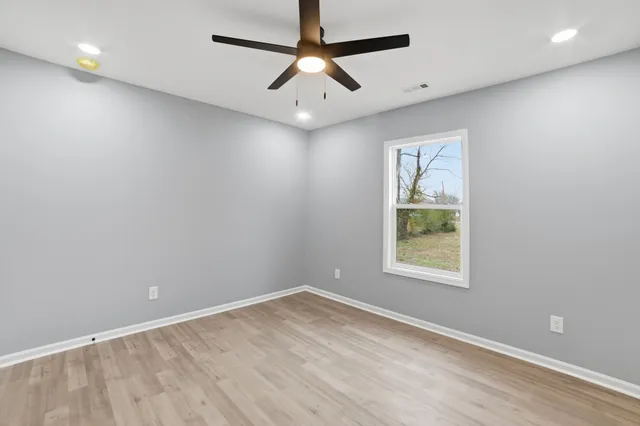 an empty room with a window and a ceiling fan