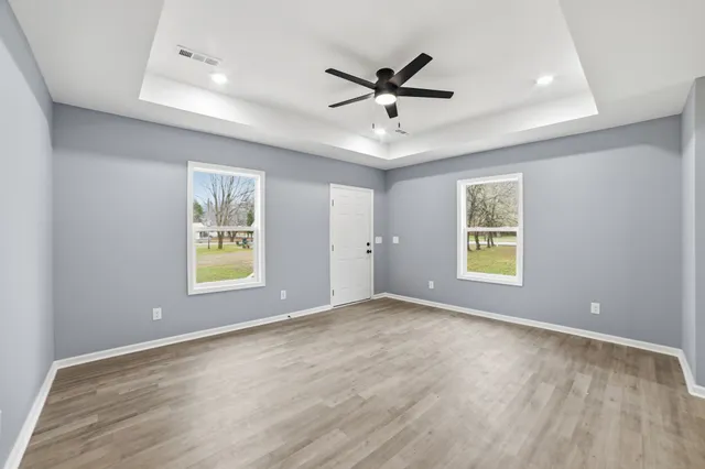 a view of a livingroom with a window a ceiling fan and wooden floor