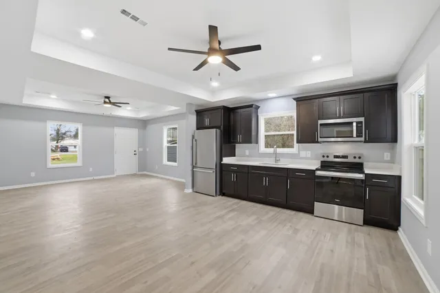 a large kitchen with stainless steel appliances granite countertop a refrigerator oven a sink dishwasher and a stove with wooden floor