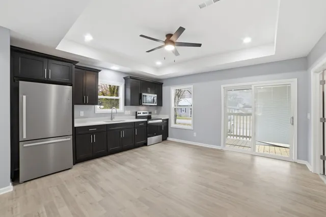 a large kitchen with a refrigerator a sink dishwasher a stove and white cabinets with wooden floor