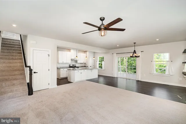 a living room with stainless steel appliances kitchen island a sink and a window