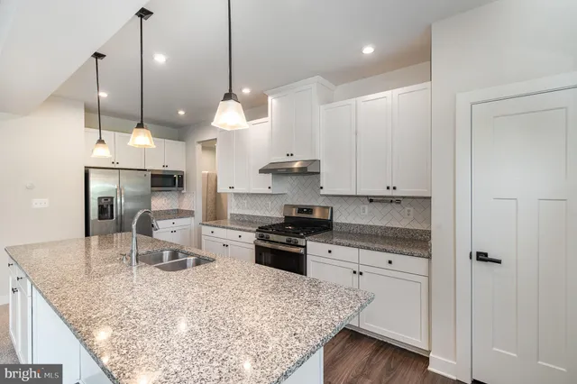 a kitchen with stainless steel appliances granite countertop a sink a stove and a refrigerator