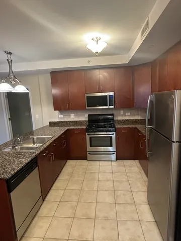 a kitchen with stainless steel appliances granite countertop a refrigerator and a stove top oven