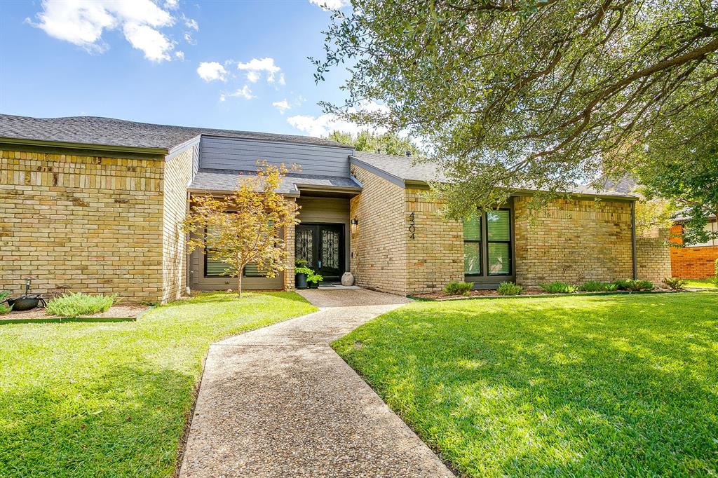 a view of a house with a yard and a large tree