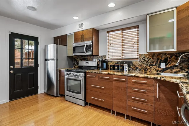 a kitchen with stainless steel appliances granite countertop a stove a sink and a refrigerator