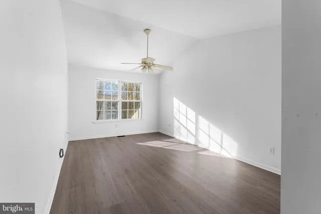 an empty room with wooden floor exposed radiator and windows