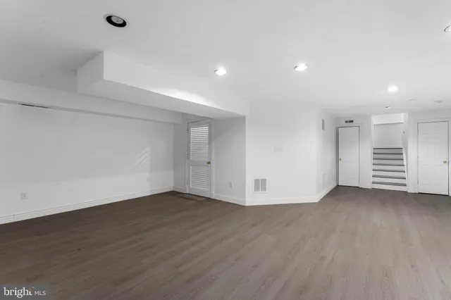 a view of an empty room with wooden floor and closet