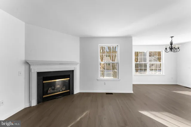 a view of an empty room with wooden floor fireplace and a window