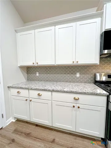 a kitchen with granite countertop a stove a sink and a microwave