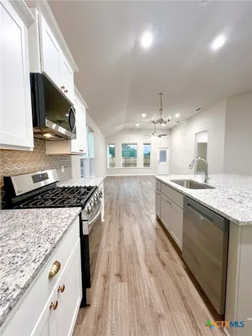 a kitchen with granite countertop a sink stove and cabinets